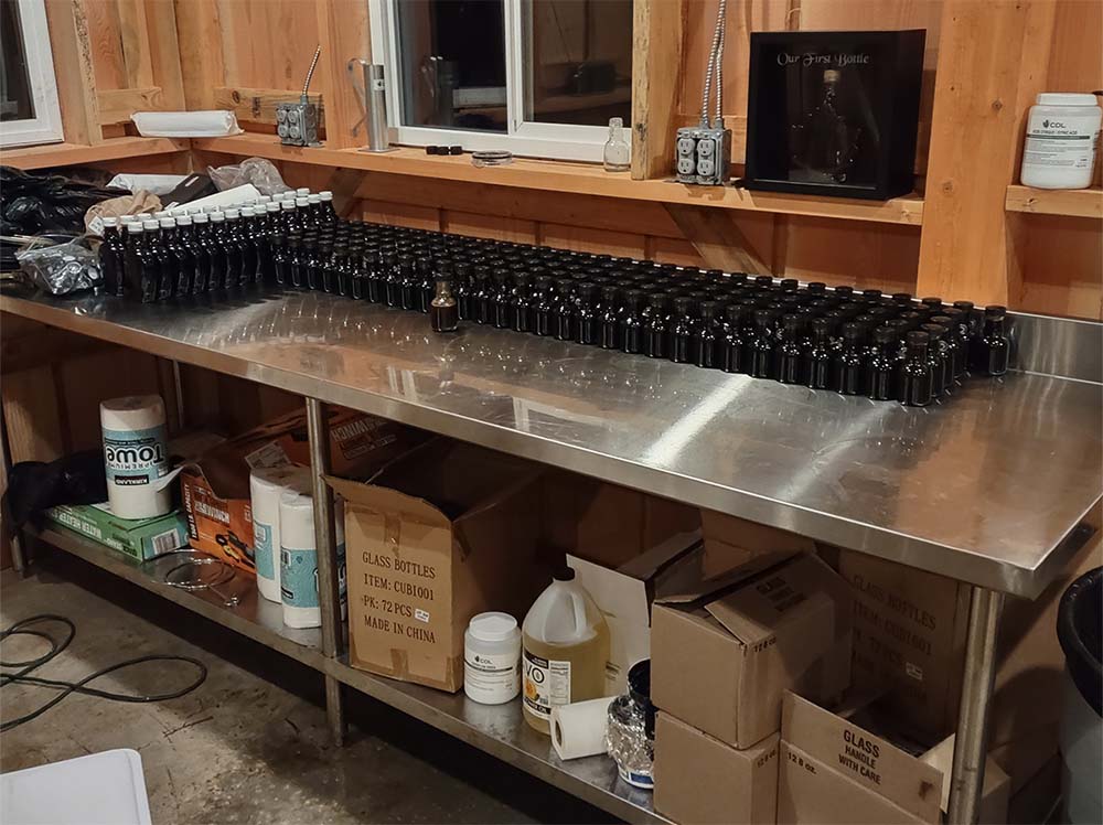 A table in the sugar shack filled with bottles of Condea's Farm bigleaf maple syrup ready for sale.