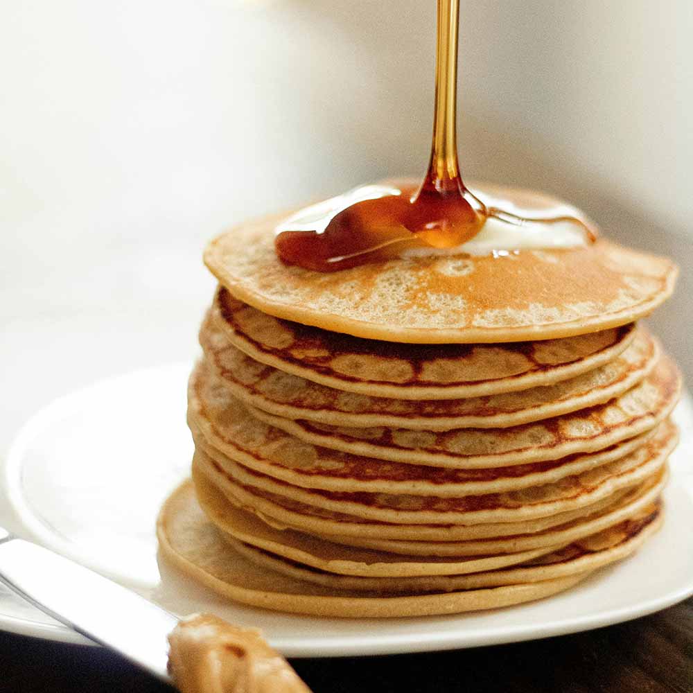 Plate of pancakes with bigleaf maple syrup being poured on the top